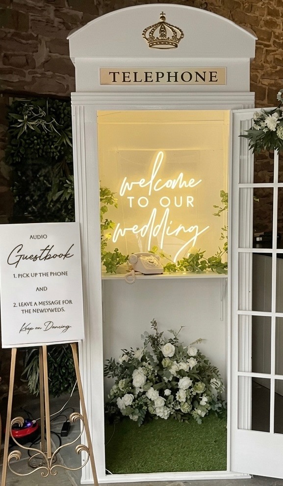 Vintage white telephone booth audio guestbook with a welcome to our wedding neon sign